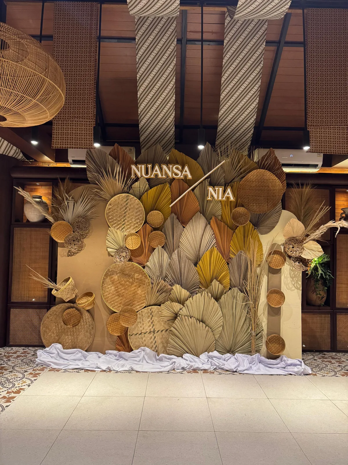 Rustic engagement backdrop with woven rattan fans and dried palm leaves