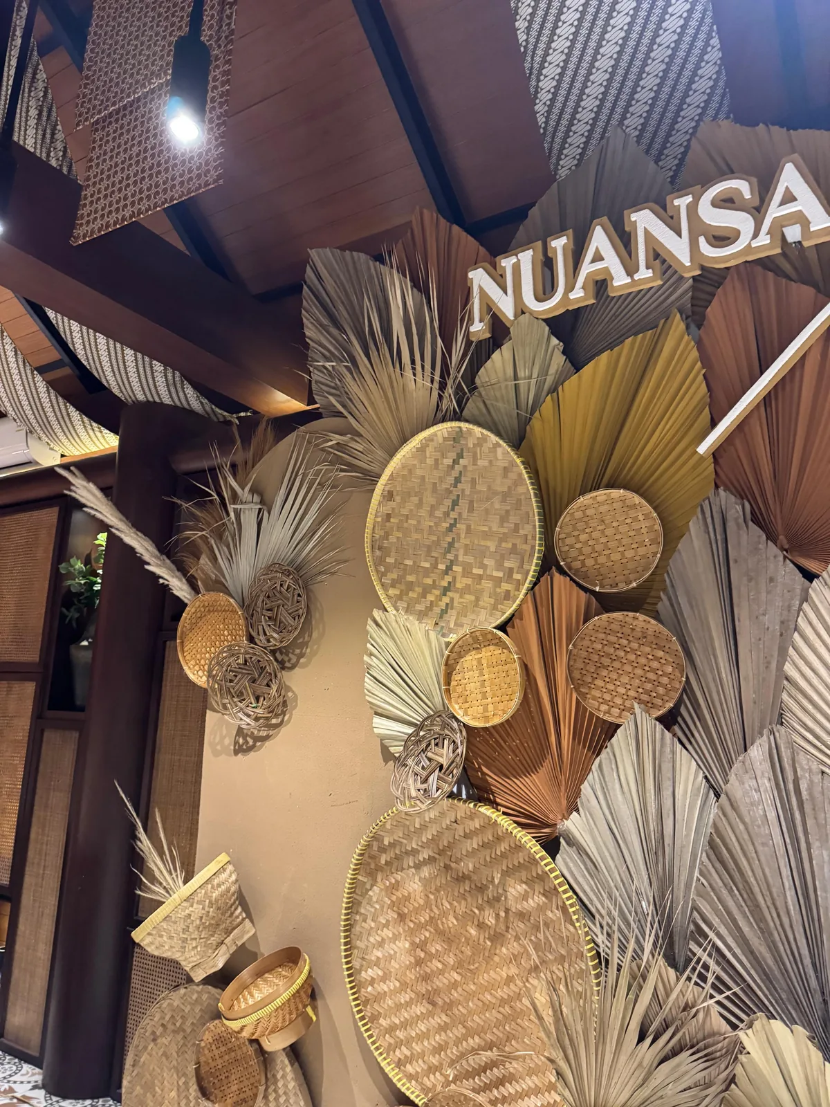 Close-up detail of engagement backdrop with woven rattan and dried palm fan decor